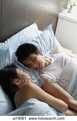 Couple lying in bed, smiling at each other View Large Photo Image Stock Image - Couple lying in bed, smiling at each other. Fotosearch