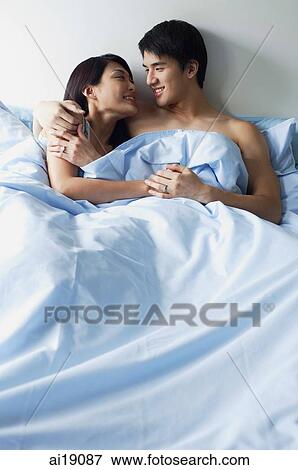 Couple lying side by side in bed, embracing View Large Photo Image Stock Photo - Couple lying side by side in bed, embracing. Fotosearch