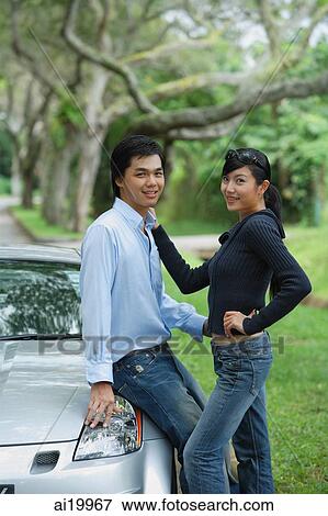 Couple next to car, looking at camera View Large Photo Image Stock Photo - Couple next to car, looking at camera. Fotosearch