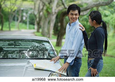 Stock Photo - Couple next to car, man turning to look at woman. Fotosearch