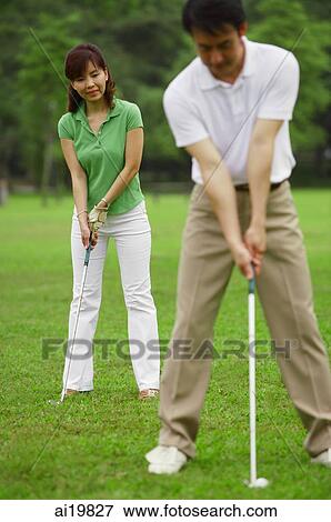 Couple on golf course, woman copying man's stance View Large Photo Image Stock Photo - Couple on golf course, woman copying man's stance. Fotosearch