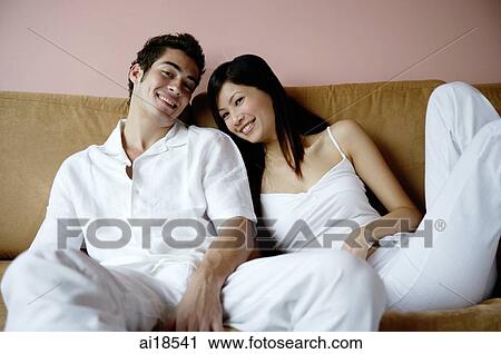 Couple on sofa, looking at camera View Large Photo Image Stock Image - Couple on sofa, looking at camera. Fotosearch