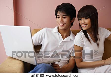 Couple on sofa, looking at laptop View Large Photo Image Stock Image - Couple on sofa, looking at laptop. Fotosearch