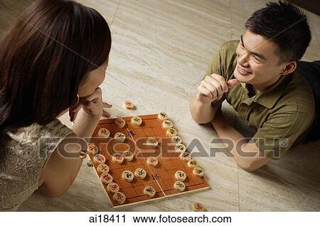 Couple playing Chinese chess, lying on floor View Large Photo Image Stock Image - Couple playing Chinese chess, lying on floor. Fotosearch