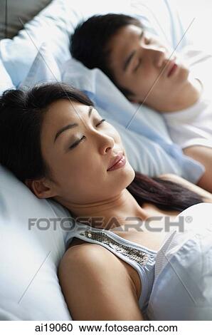 Stock Image - Couple side by side in bed, sleeping. Fotosearch