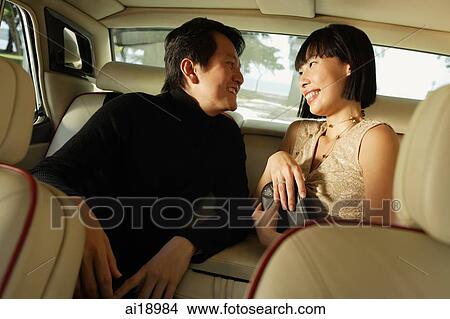 Couple sitting in backseat of car, looking at each other, smiling View Large Photo Image Picture - Couple sitting in backseat of car, looking at each other, smiling. Fotosearch