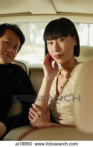 Stock Image - Couple sitting in car interior, looking at camera, portrait. Fotosearch