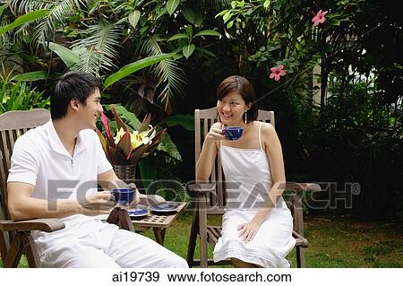 Couple sitting in garden, having a drink View Large Photo Image Stock Photo - Couple sitting in garden, having a drink. Fotosearch