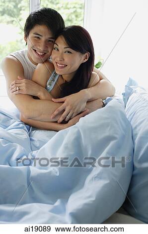 Couple sitting on bed, embracing View Large Photo Image Stock Photo - Couple sitting on bed, embracing. Fotosearch