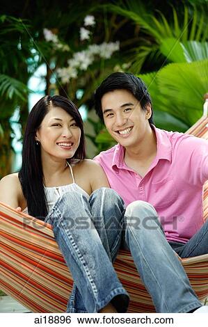 Couple sitting on hammock, smiling at camera View Large Photo Image Stock Photograph - Couple sitting on hammock, smiling at camera. Fotosearch