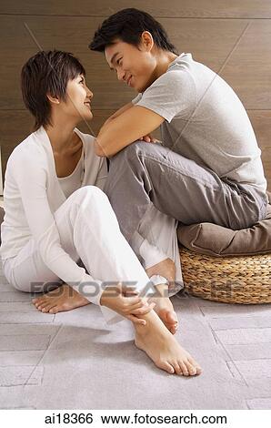 Couple sitting side by side, looking at each other View Large Photo Image Stock Photograph - Couple sitting side by side, looking at each other. Fotosearch