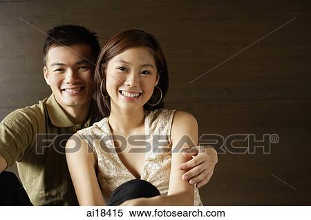 Couple sitting side by side, looking at camera View Large Photo Image Stock Photography - Couple sitting side by side, looking at camera. Fotosearch