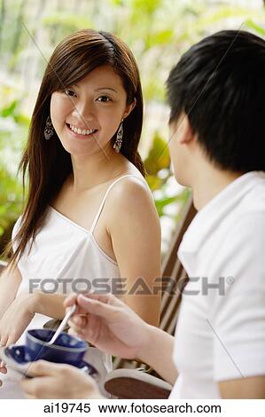 Couple sitting side by side on patio, man holding cup and saucer, woman smiling at camera View Large Photo Image Stock Photography - Couple sitting side by side on patio, man holding cup and saucer, woman smiling at camera. Fotosearch
