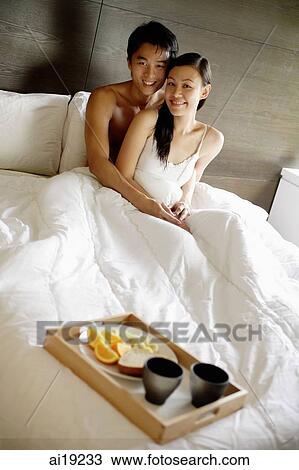 Couple sitting up in bed, looking at camera, breakfast tray at foot of bed View Large Photo Image Stock Image - Couple sitting up in bed, looking at camera, breakfast tray at foot of bed. Fotosearch