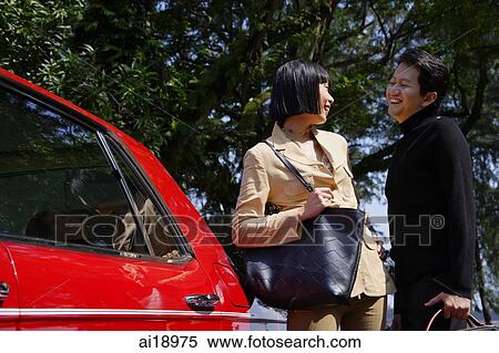 Couple smiling at each other, standing next to car View Large Photo Image Stock Photography - Couple smiling at each other, standing next to car. Fotosearch