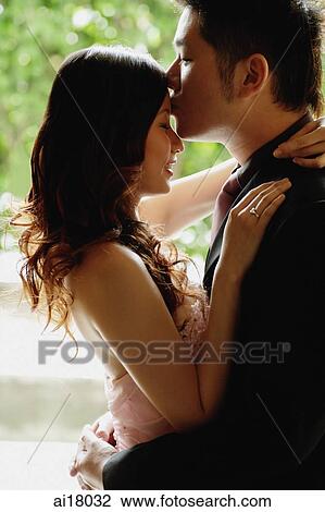 Couple standing face to face, man kissing woman on forehead View Large Photo Image Stock Image - Couple standing face to face, man kissing woman on forehead. Fotosearch