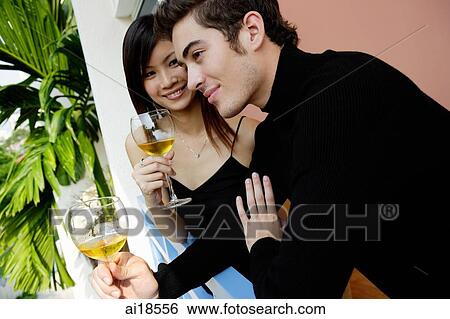 Couple standing in balcony with wine glasses View Large Photo Image Stock Photograph - Couple standing in balcony with wine glasses. Fotosearch