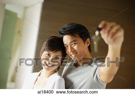 Couple standing side by side looking at camera, man holding key, selective focus View Large Photo Image Stock Image - Couple standing side by side looking at camera, man holding key, selective focus. Fotosearch