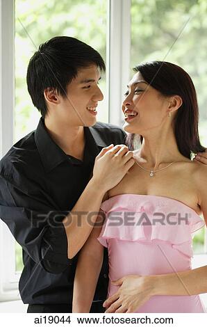 Couple standing side by side, looking at each other View Large Photo Image Picture - Couple standing side by side, looking at each other. Fotosearch