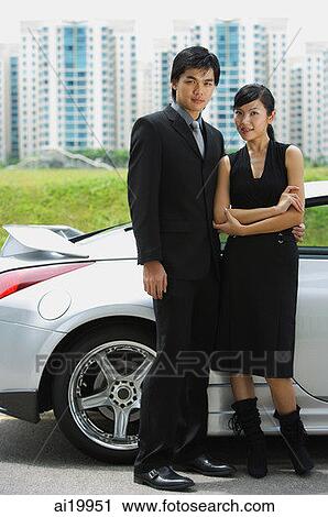 Couple standing side by side, silver sports car behind them View Large Photo Image Stock Image - Couple standing side by side, silver sports car behind them. Fotosearch