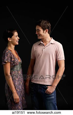 Stock Image - Couple standing, smiling at each other. Fotosearch