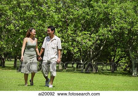 Stock Image - Couple walking in park, holding hands. Fotosearch