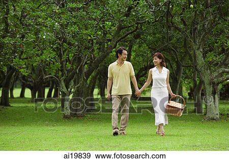 Couple walking in park, woman carrying picnic basket View Large Photo Image Stock Photo - Couple walking in park, woman carrying picnic basket. Fotosearch