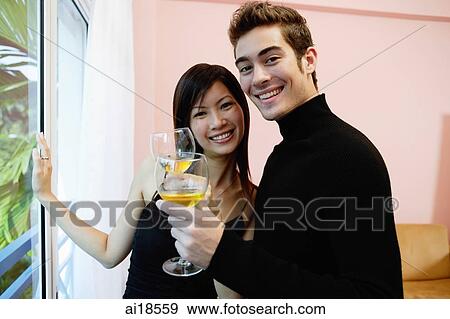 Stock Photo - Couple with wine glasses, smiling at camera. Fotosearch