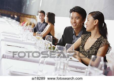 Stock Photo - Couples dining in restaurant, man smiling at camera. Fotosearch