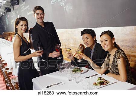 Couples in restaurant, holding wine glasses, smiling at camera View Large Photo Image Stock Photo - Couples in restaurant, holding wine glasses, smiling at camera. Fotosearch