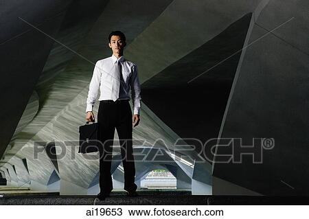 Executive holding briefcase, looking at camera View Large Photo Image Stock Image - Executive holding briefcase, looking at camera. Fotosearch