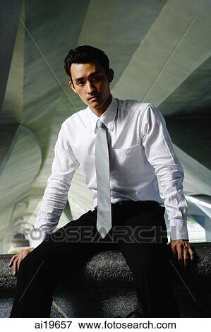 Executive in shirt and tie, sitting on ledge, looking at camera View Large Photo Image Stock Photo - Executive in shirt and tie, sitting on ledge, looking at camera. Fotosearch