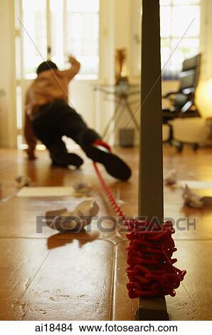 Picture - Executive tied to pole by chain, crawling towards door. Fotosearch