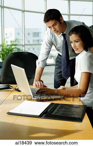 Executives looking at laptop in office View Large Photo Image Stock Photo - Executives looking at laptop in office. Fotosearch