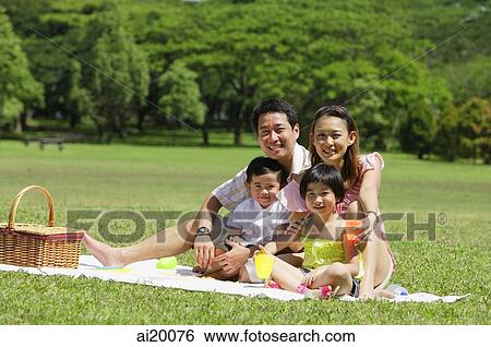 Stock Photograph - Family of four having a picnic, looking at camera. Fotosearch