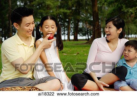 Family of four in park, father feeding daughter an apple View Large Photo Image Stock Image - Family of four in park, father feeding daughter an apple. Fotosearch