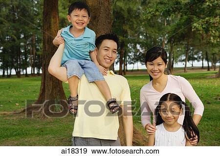 Family of four, standing in park, smiling at camera View Large Photo Image Stock Photo - Family of four, standing in park, smiling at camera. Fotosearch