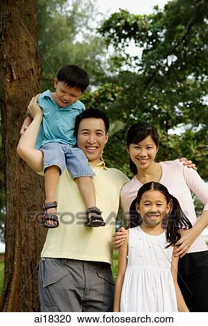 Stock Image - Family of four, standing outdoors, family portrait. Fotosearch