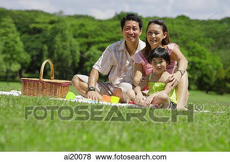 Stock Photo - Family of three having a picnic, looking at camera. Fotosearch