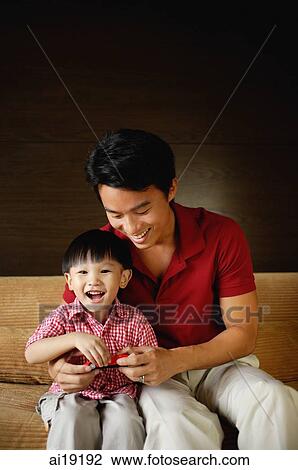 Father and young son sitting on sofa, son holding toy car View Large Photo Image Stock Image - Father and young son sitting on sofa, son holding toy car. Fotosearch