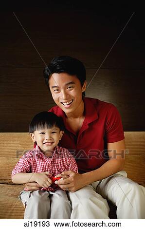 Father and young son sitting on sofa, smiling at camera View Large Photo Image Stock Image - Father and young son sitting on sofa, smiling at camera. Fotosearch