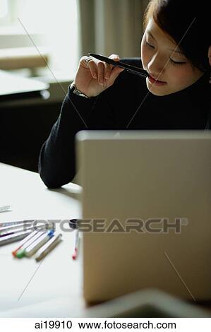 Stock Image - Female designer with pen in mouth. Fotosearch