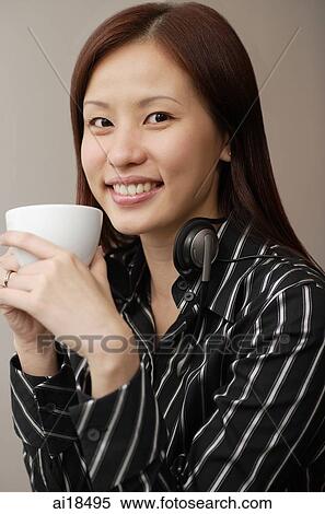 Stock Photography - Female executive holding mug, smiling at camera. Fotosearch