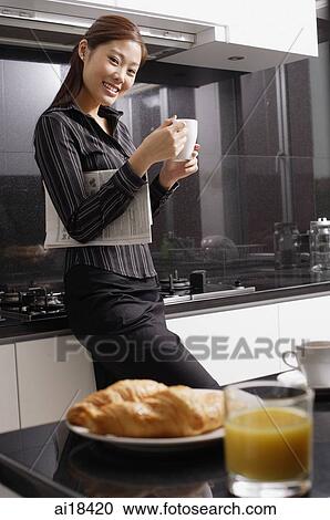 Female executive standing in kitchen, holding mug View Large Photo Image Stock Image - Female executive standing in kitchen, holding mug. Fotosearch