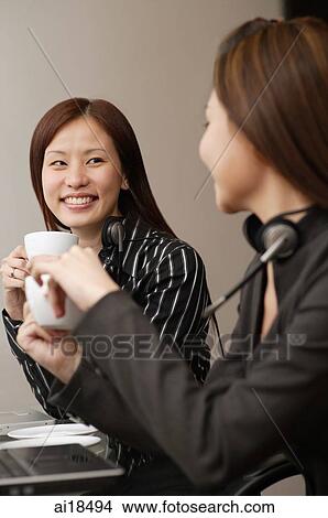 Picture - Female executives having a coffee break, sitting side by side. Fotosearch