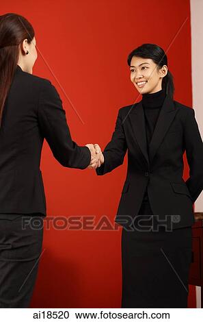 Stock Image - Female executives shaking hands. Fotosearch