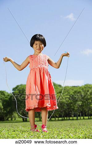 Stock Photo - Girl in park, holding skipping rope, looking at camera. Fotosearch