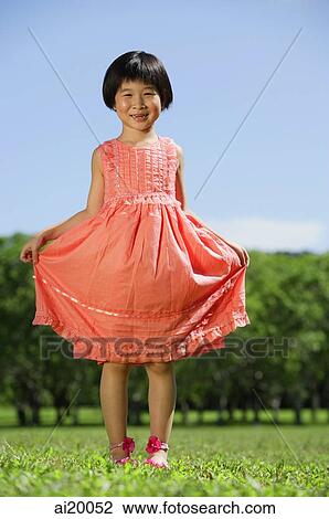 Girl in peach dress, standing in park View Large Photo Image Stock Image - Girl in peach dress, standing in park. Fotosearch