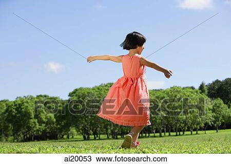 Girl in peach dress, walking on grass, arms outstretched View Large Photo Image Stock Image - Girl in peach dress, walking on grass, arms outstretched. Fotosearch