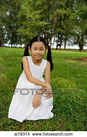 Girl in white dress, crouching on grass View Large Photo Image Picture - Girl in white dress, crouching on grass. Fotosearch